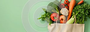 Organic local vegetables in reusable tote bag on light green background photo