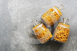 A variety of pasta in glass jars on a gray background. Top view, flat lay,copy space