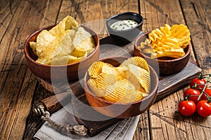 Variety of Potato chips - Crinkle, homemade, hot BBQ. Wooden background. Top view