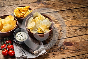 Variety of Potato chips - Crinkle, homemade, hot BBQ. Wooden background. Top view. Copy space