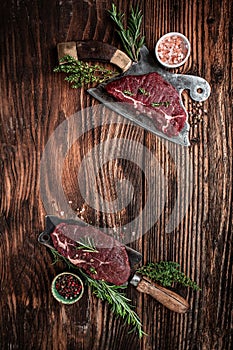 Variety of raw black angus prime meat steaks beef rump steak for grilling on old meat cleaver on dark background. vertical image.