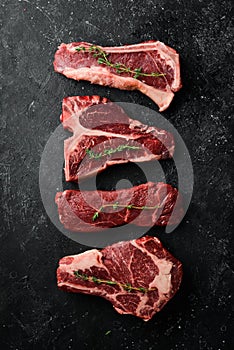 Variety of raw black Angus Prime meat steaks: t-bone, striploin, Rib eye, new york steak. Top view.