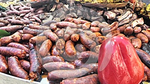 Variety of sausages grilled over charcoal on a grill, accompanied by peppers