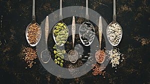 A variety of seeds in spoon on dark background. Flat lay, close-up. Chia, flax, pumpkin, sunflower, coriander, sesame, black