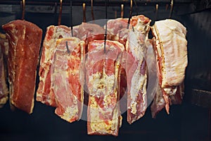 A variety of smoked meat products: sausages, ham, bacon, ribs in the smokehouse close up.