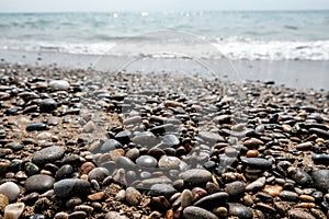 Variety of smooth pebbles, rocks and stones at seashore. Quiet peaceful beach with water waves coming in. Escaping to dream