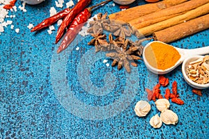 Variety of spices and herbs in a cup and spoon on a wooden background