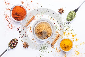 Variety of spices and herbs in spoons and bowls on white background. Top view. Cooking ingredients and condiments concept