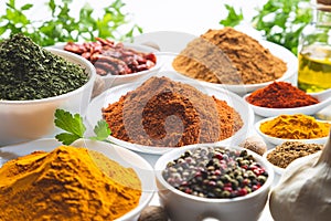 Variety of spices and herbs in white bowls on white background. selective focus. Cooking ingredients and condiments concept