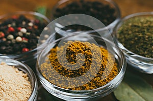 Variety of spices in round glass bowls - ground ginger, hops-suneli, kari, black pepper and mix