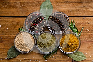 Variety of spices in round glass bowls - ground ginger, hops-suneli, kari, black pepper and a mixture