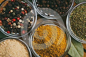 Variety of spices in round glass bowls - ground ginger, hops-suneli, kari, black pepper and a mixture