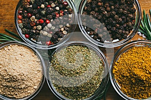 Variety of spices in round glass bowls - ground ginger, hops-suneli, kari, black pepper and a mixture