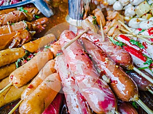 Variety of streamed sausages and meatballs dipped in hot and spicy chilli sauce