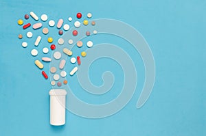 Variety of tablets and pills.Pharmaceuticals and antibiotics heart-shaped bottle on blue background.