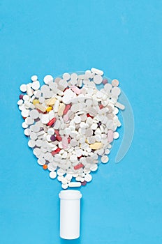 Variety of tablets and pills.Pharmaceuticals and antibiotics heart-shaped bottle on blue background.