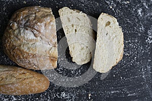 Variety of traditional breads with bread slices on floury black background.Concept of recipe, baking and healthy ingredients