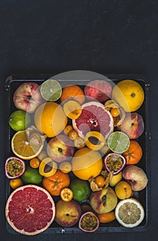 Variety of tropical colorful summer fruits on black background with copy space