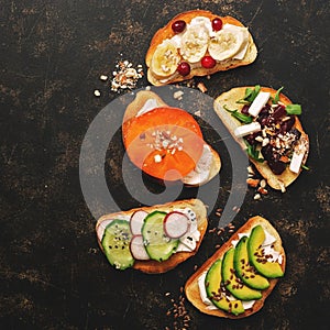 A variety of vegan sandwiches with vegetables and fruits on a dark rustic background. Top view, flat lay. The concept of healthy