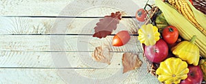 Variety of vegetables and fruits in a wicker basket on a wooden background