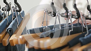 A variety of women`s denim pants hanging on a hanger. Woman chooses her clothes in the store. Hands close up