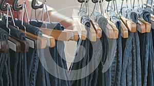 A variety of women`s denim pants hanging on a hanger. Woman chooses her clothes in the store. Hands close up
