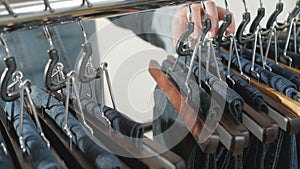 A variety of women`s denim pants hanging on a hanger. Woman chooses her clothes in the store. Hands close up