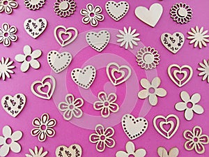 A variety of wood shaped  hearts and flowers on a pink background