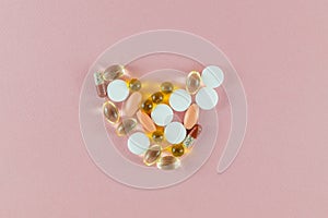 Various antibiotic tablets, vitamin D capsules, vitamin C for the treatment of coronavirus, covid-19, and other diseases on a pink