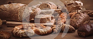 Various baked breads and rolls on rustic wooden table