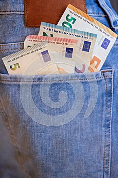 Money euro banknotes in blue trousers pocket. Close up money in back pocket.