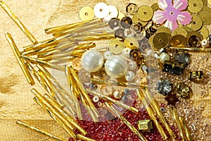 Various beads and sequins on yellow shiny fabric