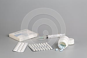 Various boxes of medication, blisters with pills, syringes and white bottles with medication