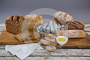 Various bread loaves with butter on wooden surface