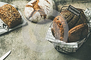 Various bread loaves on grey concrete background, copy space