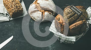 Various bread loaves over black background, copy space, horizontal composition