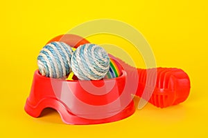 Various bright pet toys and bowl on yellow background