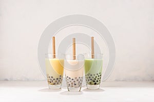 Various Bubble Tea in glasses with drink straws on white background
