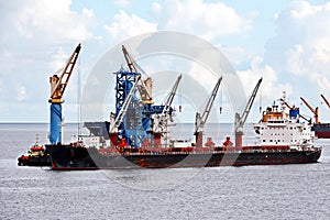 Various bulk carriers, vessels, and tugboats in port under cargo operations and underway. Port of Muara Pantai, Indonesia, January