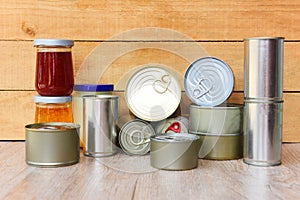 Various canned food in metal cans on wooden background - canned goods non perishable food storage goods in kitchen home or for