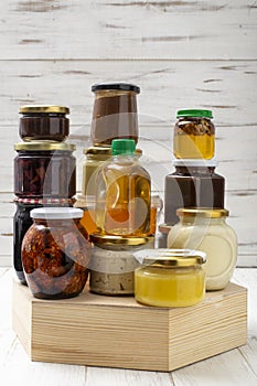 Various canned foods in jars on a light wooden background. Organic food