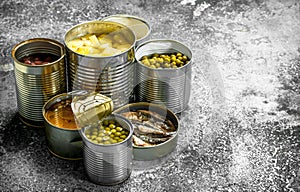 Various canned foods with meat, fish, vegetables and fruits in tin cans.