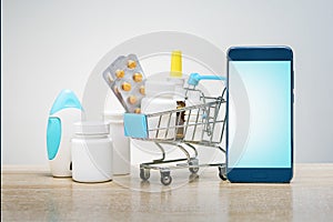 Various capsules, tablets, medicine in shop trolley and mobile phone for medicine online payment.