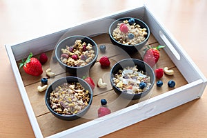 various cereals in small bowls with fresh and dried fruits on a tray