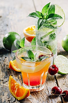 Various cocktail beverages mix with fruit and alcohol on wooden table from above. Tropical juice drink with orange, lime, cherry