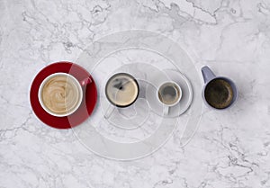 Various coffee in different cups on marble background. Flat lay top view composition