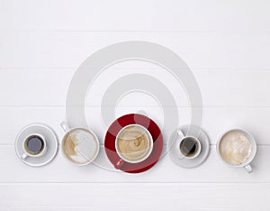 Various coffee in different cups on white wooden background