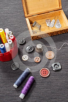 Various colored buttons for clothes lie on the table. Sewing accessories are lying next to you. Sewing a button to clothes. The ne