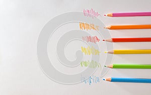 Various colored pencils on white striped paper top view