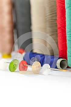 Various colored spools and buttons on an needle housework hobby tailoring concept